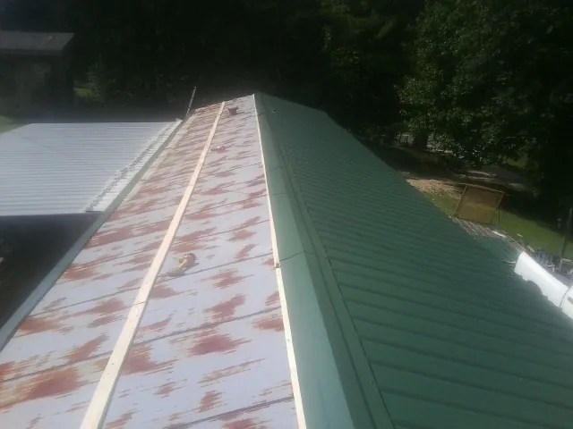 Old rusted panels beside newly installed green metal roofing — Wind Damage Roof Repair by Roofing Brothers in Schertz