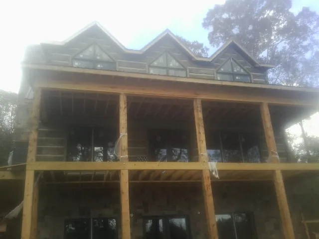 Dormers and porch framing on a large log home under construction — Roof Coating work by our crew in Schertz