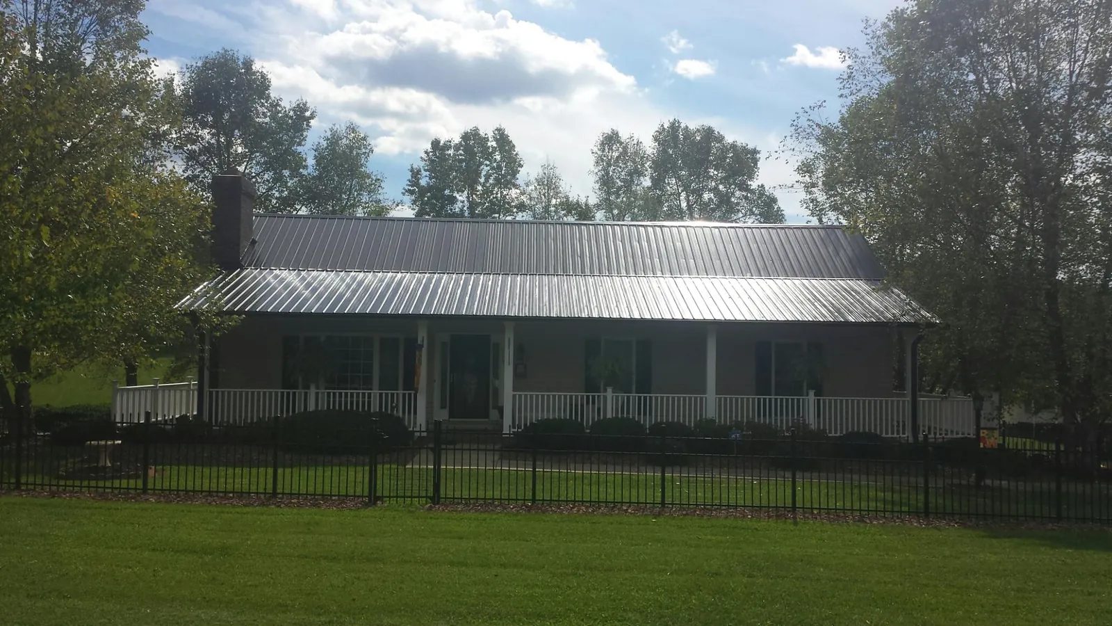 Gray metal roof on a brick ranch with a full width front porch — Gutter Guard Installation work by our crew in Schertz