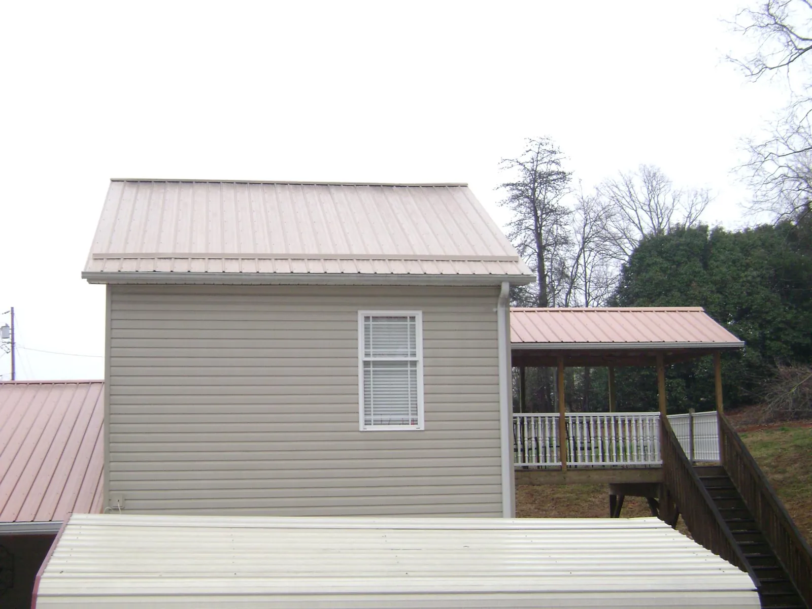 Tan metal roofs on a two story addition and attached porch, from a Roof Replacement job in Schertz