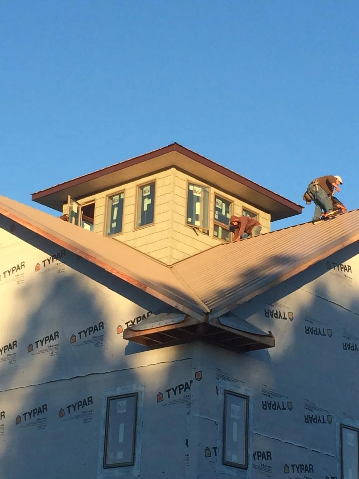 Roofers working around a rooftop cupola on a new metal roof at sunset — Roof Waterproofing in Schertz by Roofing Brothers